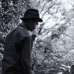 Side view of mature man wearing hat standing in forest