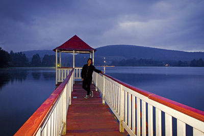 Rear view of man standing on jetty against lake