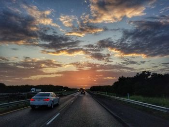 Cars on road against sky during sunset