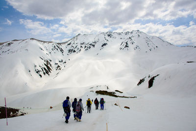 People walking on snowcapped mountain against sky