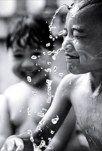 Close-up portrait of shirtless man splashing water