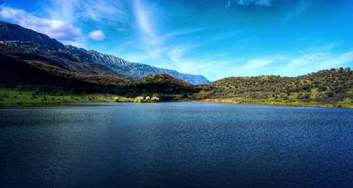 Scenic view of lake and mountains against blue sky