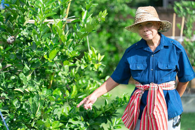 Senior man wearing hat standing by plants outdoors