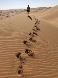 Woman walking on sand dune at desert