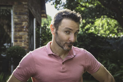 Young man looking away, pulling a silly face while standing outdoors.