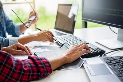 Midsection of man using mobile phone while sitting on table