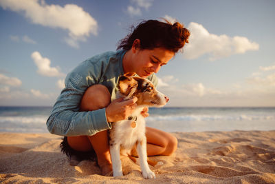 Woman with dog at beach against sky