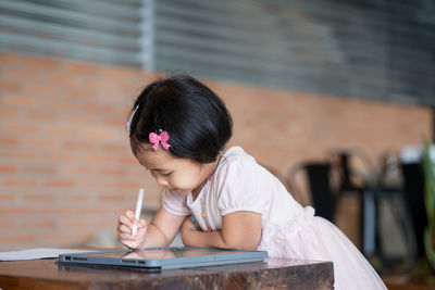 Girl looking away while sitting on table