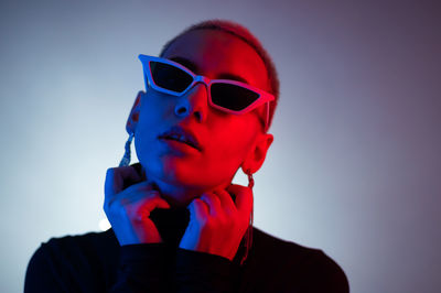 Portrait of young man wearing sunglasses against gray background