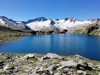 Scenic view of lake and mountains against clear blue sky