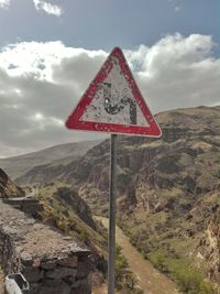 Road sign by mountain against sky