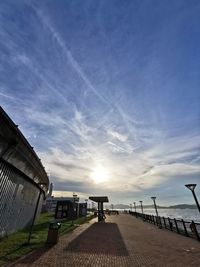 Footpath by sea against sky during sunset