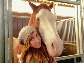 Close-up portrait of woman with horse in stable