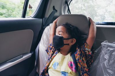 Young girl looking outside while sitting in car