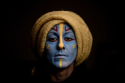 Close-up portrait of young woman against black background