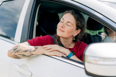 Young woman using mobile phone while sitting in car
