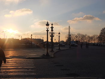 Street by city against sky during sunset