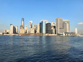 Sea by buildings against blue sky