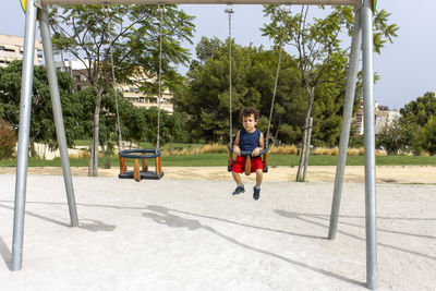 Young child on swing set at an urban park playground.