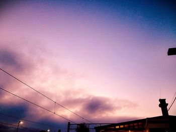 Low angle view of power lines against cloudy sky