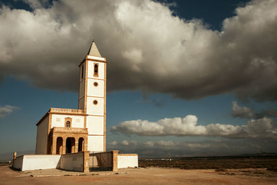 Church on beach by sea against sky