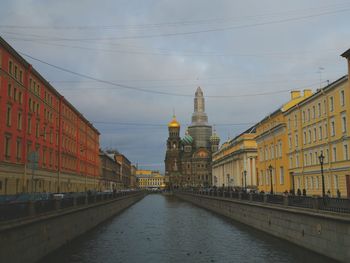 Canal amidst buildings against sky in city