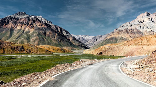 Scenic view of mountains against sky with river flowing along side