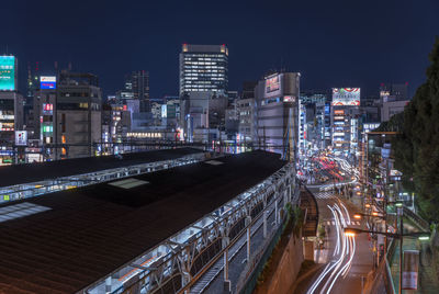 High angle view of light trails on road amidst buildings in city at night