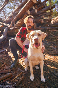 Portrait of young tattoed man with his dog in the forest