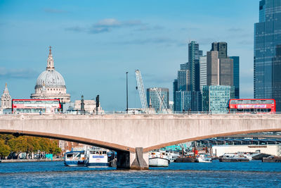 Red double decker bus crossing a bridge in london