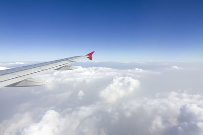 Airplane flying over clouds against blue sky