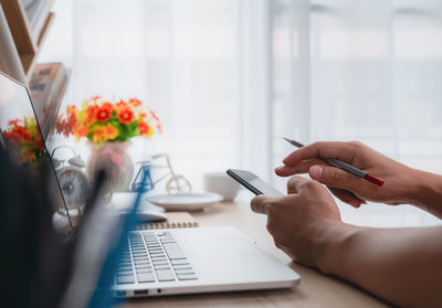 Midsection of person using mobile phone on table