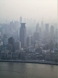 Cityscape by river against sky in city