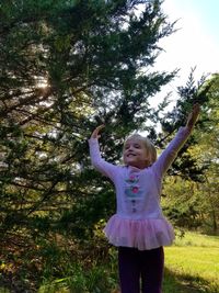 Full length of smiling boy standing against tree