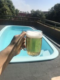 Midsection of person holding ice cream in swimming pool