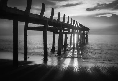 Pier over sea against cloudy sky