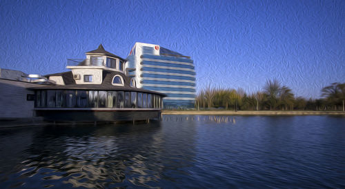 Reflection of building in lake against clear blue sky