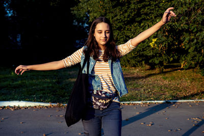 Portrait of smiling young woman standing on road