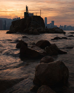 Rocks on beach against sky during sunset