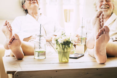 Midsection of woman sitting on table at home