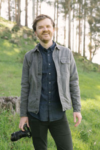 Man smiling outdoors looking into camera in casual dress with camera