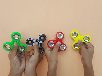 Close-up of hands holding fidget spinners against beige background