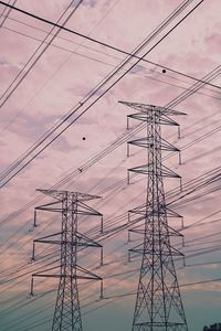 Low angle view of silhouette electricity pylon against sky during sunset