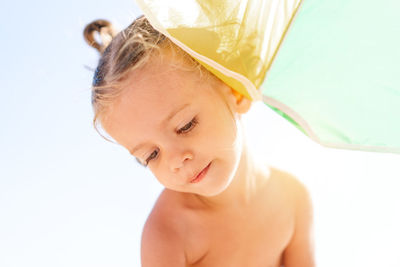 Close-up of shirtless girl sitting outdoors