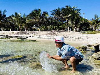 Full length of man splashing water at beach