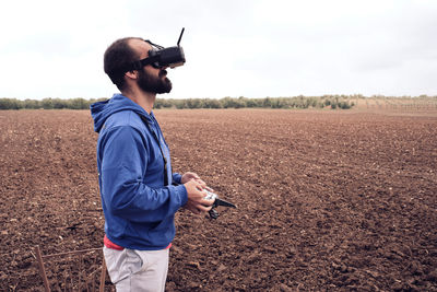 Young man with black beard flies drone watching him through glasses