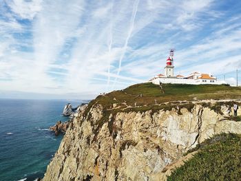 Lighthouse by sea against sky