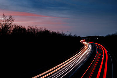 Light trails on road against sky at night