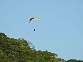 Person paragliding against clear sky