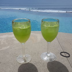 Wineglass on table by sea against sky